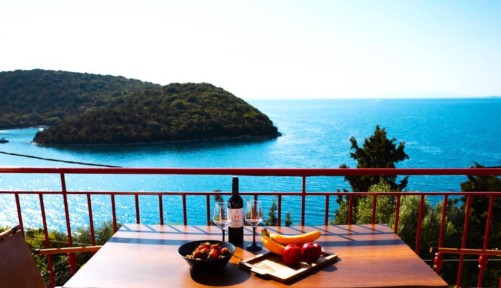 a table with a bottle of wine and fruit on a balcony at Home Sweet Home Unique Sea View in Sivota
