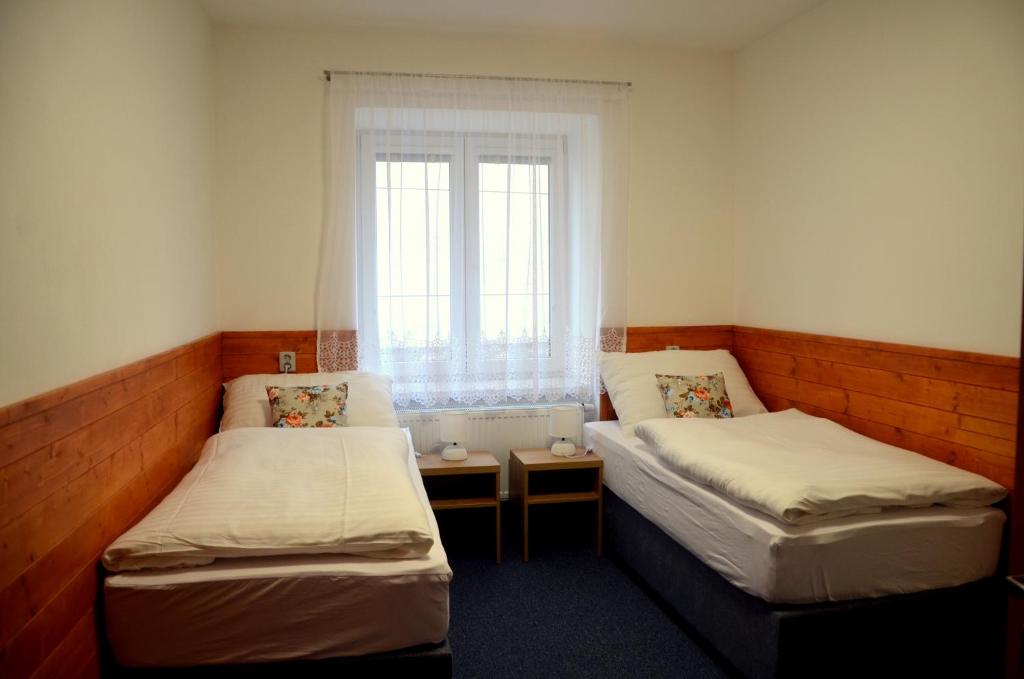 2 camas en una habitación pequeña con ventana en Penzion U Cyrila, en Moravská Třebová