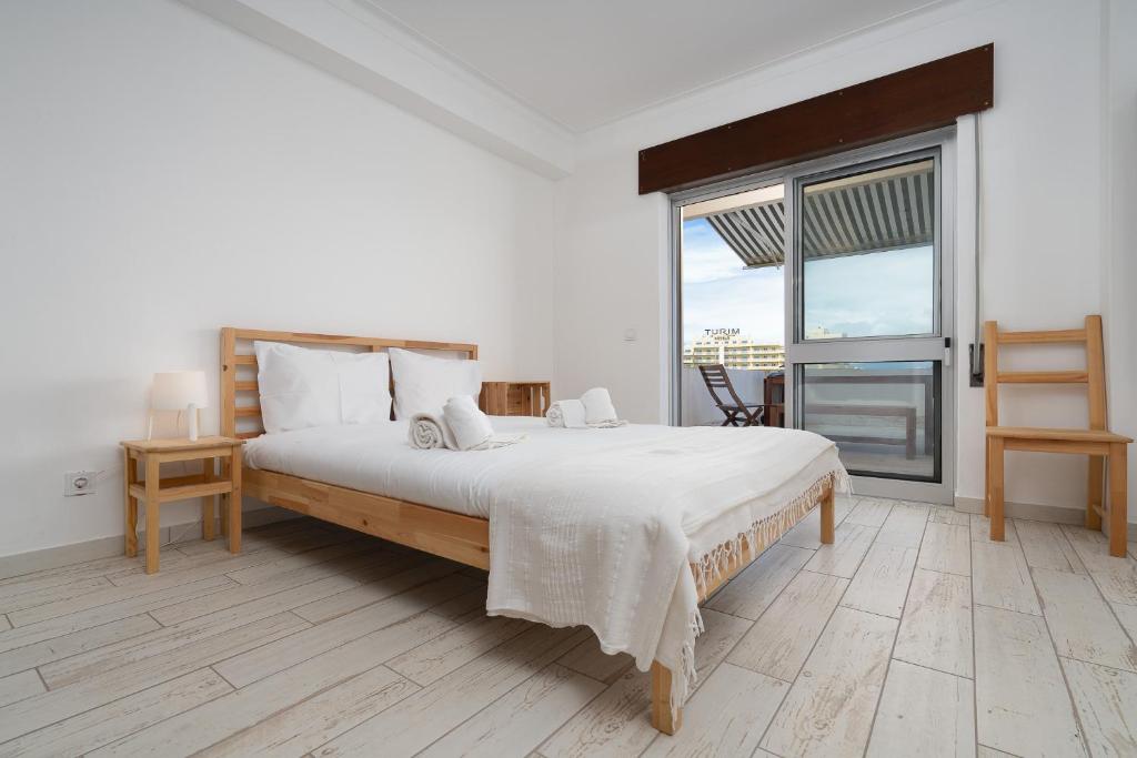 a white bedroom with a large bed and a window at Praia do Amado Flat by LovelyStay in Portimão