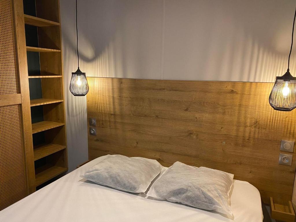 a bedroom with a bed with two lights on it at Mobil home PREMIUM 35m2 3 chambres 6 personnes in Arès