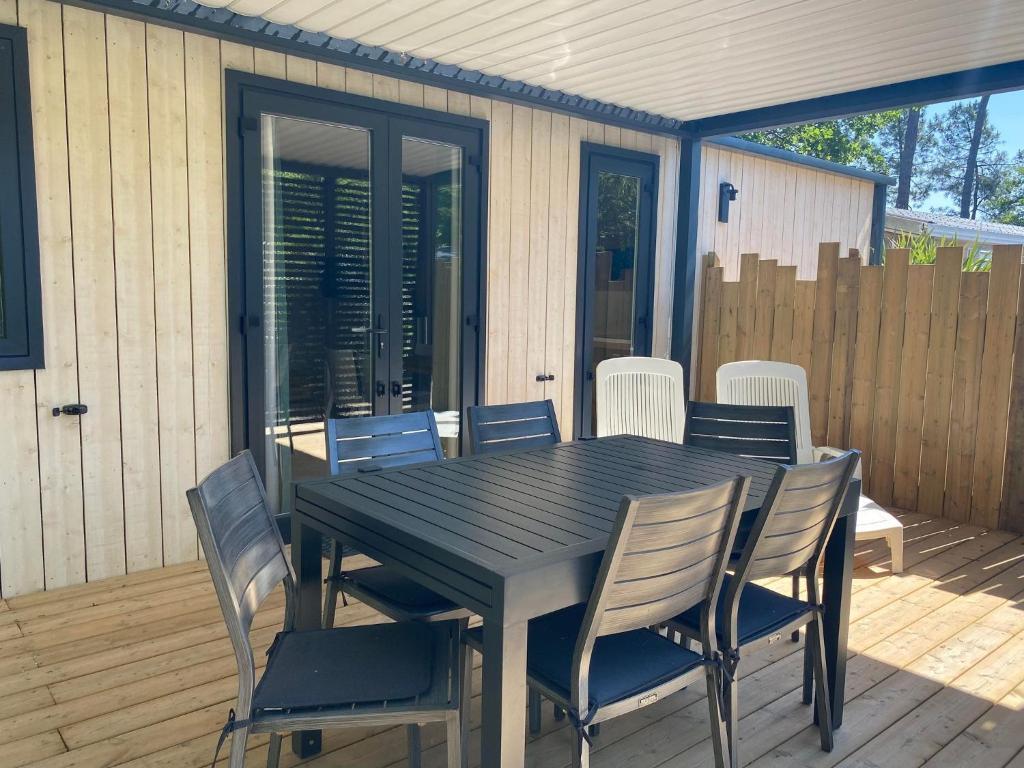 a wooden table and chairs on a deck at Mobil home PREMIUM 35m2 3 chambres 6 personnes in Arès