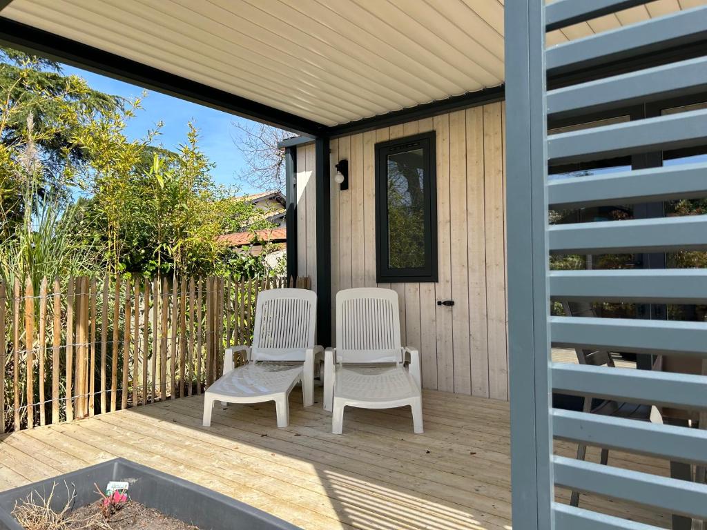 two white chairs sitting on a wooden deck at Mobil home PREMIUM 35m2 3 chambres 6 personnes in Arès