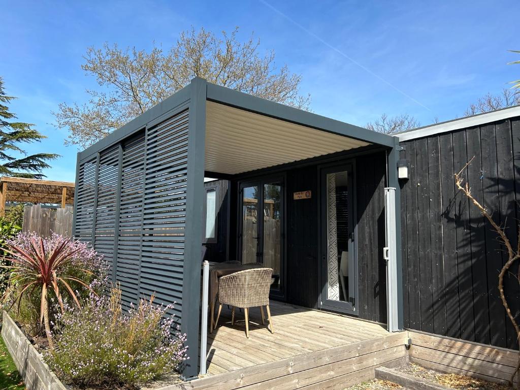a black shed with a chair on a wooden deck at Mobil home PREMIUM 35m2 3 chambres 6 personnes in Arès