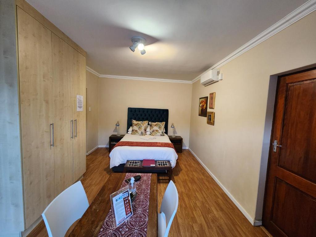 a bedroom with a bed and a table and chairs at Jenvey House Selfcatering Apartments & BnB in Port Elizabeth