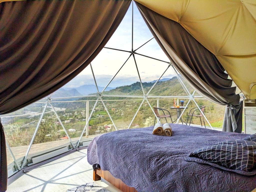 a bed in a room with a large window at 4 seasons. 4 სეზონი Glamping Georgia Racha in Ambrolauri