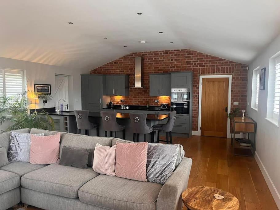 a living room with a couch and a kitchen at 2 Bedroom Barn Conversion in Leicester