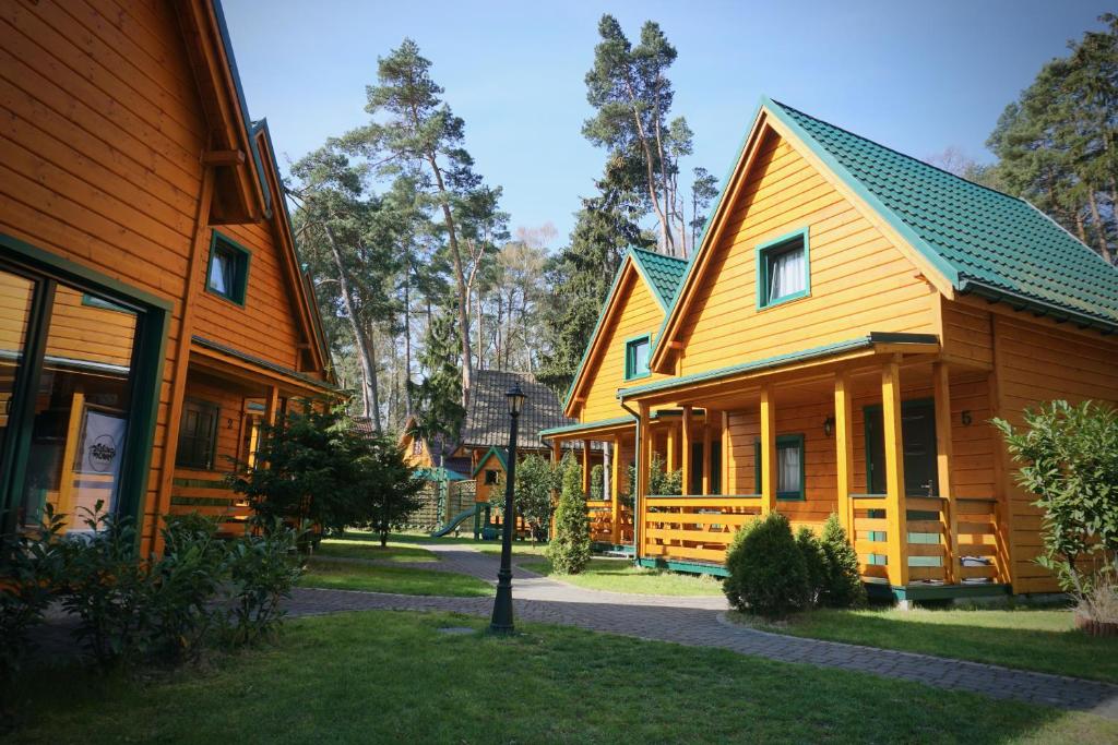 rząd drewnianych domów z zielonym dachem w obiekcie Zielone Domki w Pobierowie