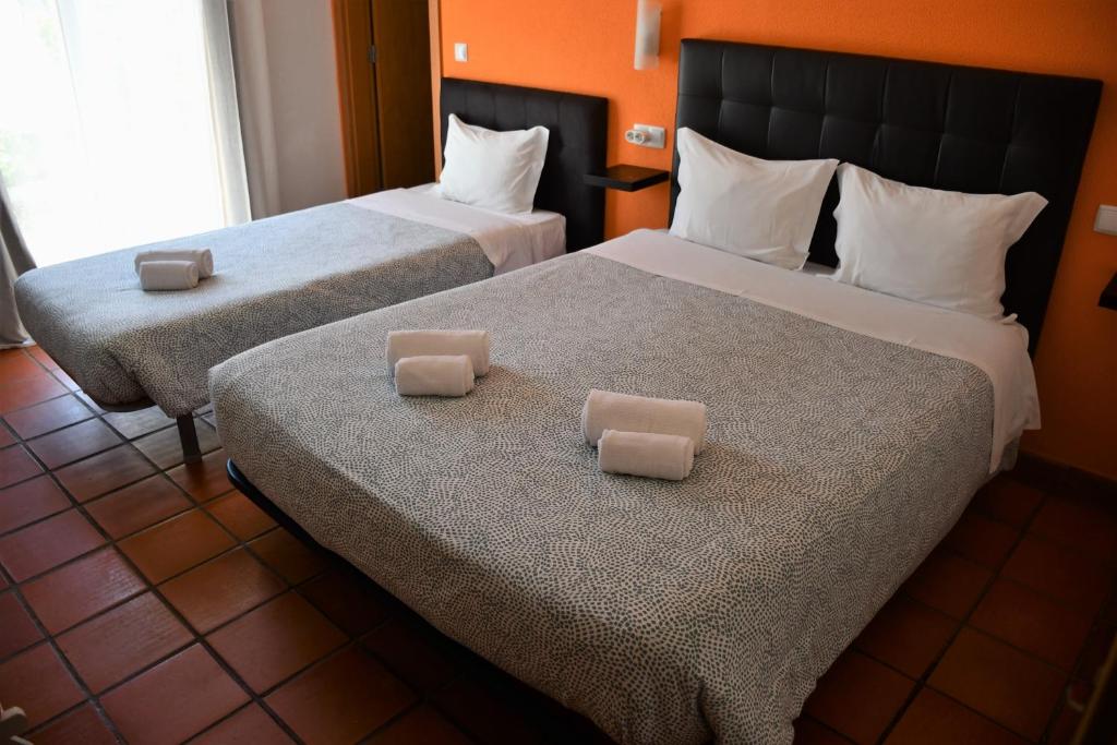 zwei Betten in einem Hotelzimmer mit zwei Handtüchern darauf in der Unterkunft Alojamentos Vitinho - Vila Nova Milfontes in Vila Nova de Milfontes