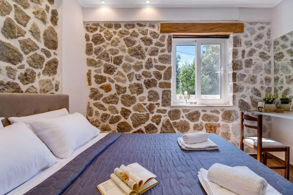 a bedroom with a bed and a stone wall at Sea view apartments in Tsoukaladhes