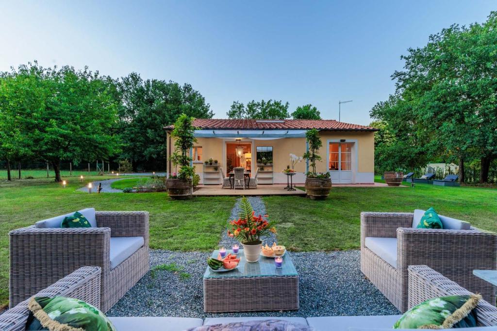 einen Hinterhof mit Korbmöbeln und einem Haus in der Unterkunft Villa Bassotta, a Charming Cottage in Lucca