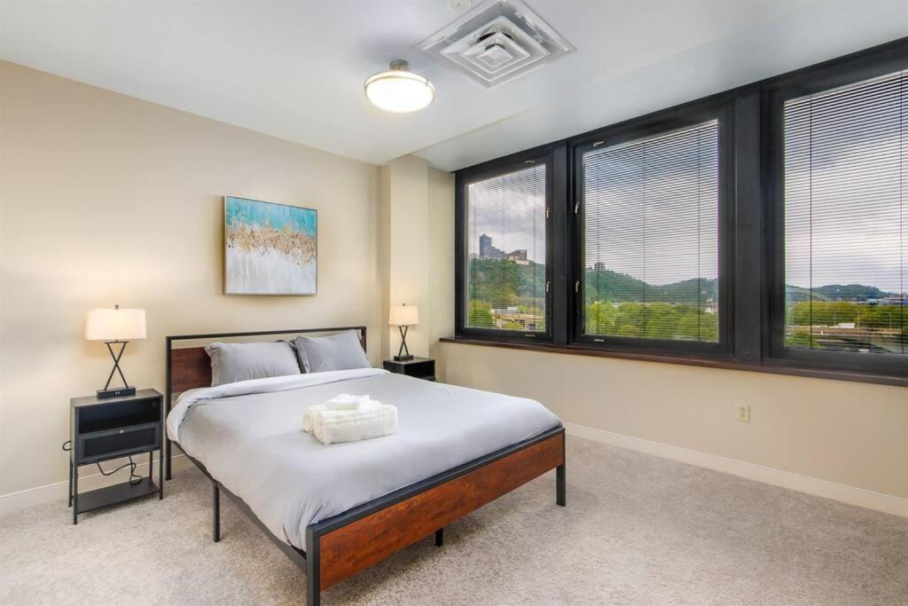 a bedroom with a large bed and windows at Sweeping Stadium Views 24-7 Valet Gym WiFi in Pittsburgh