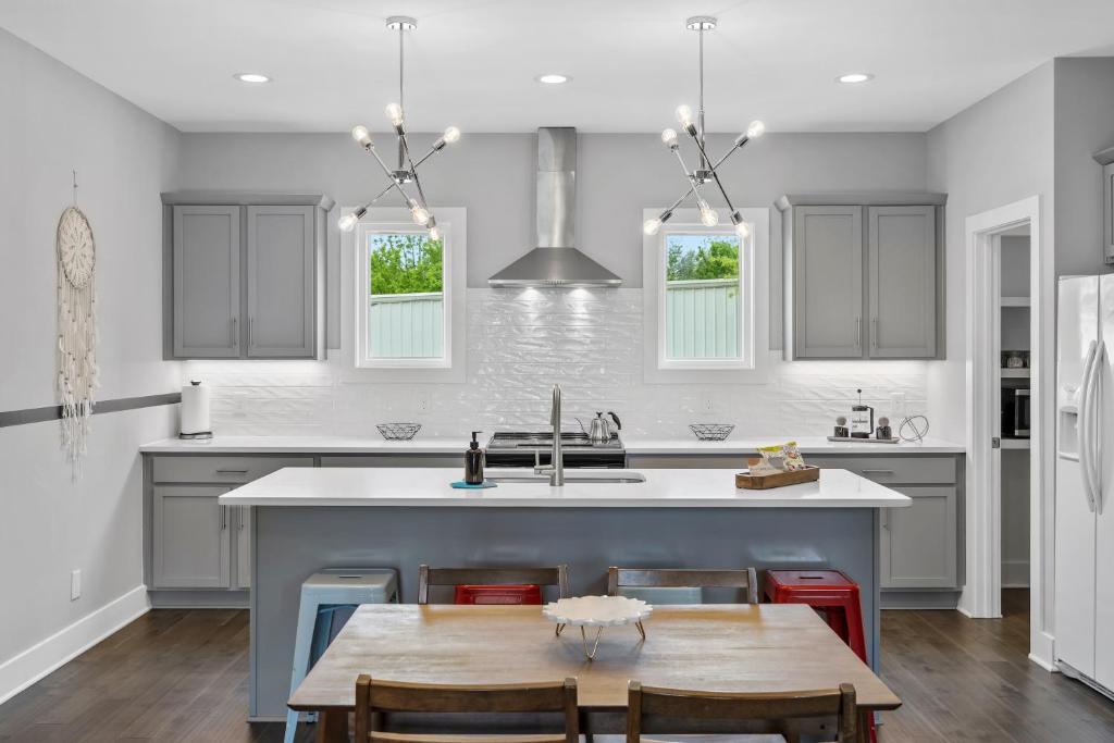 a kitchen with gray cabinets and a kitchen island with a table at Rhythm & View - Large Groups in Nashville