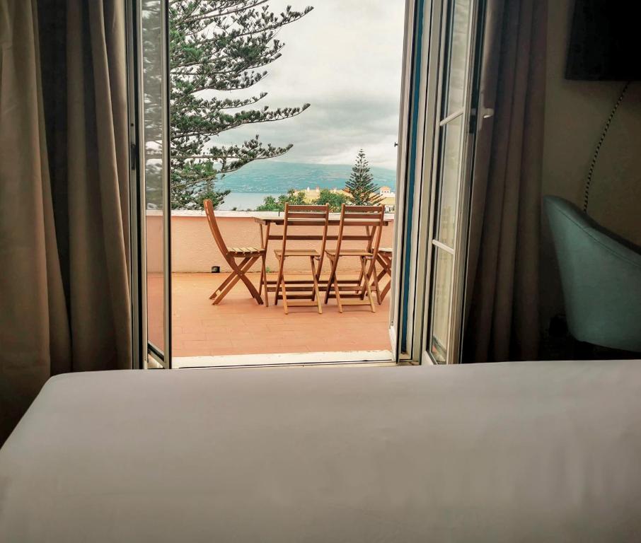 a bedroom with a view of a balcony with a table and chairs at Garden's Nest - North Villa in Conceição