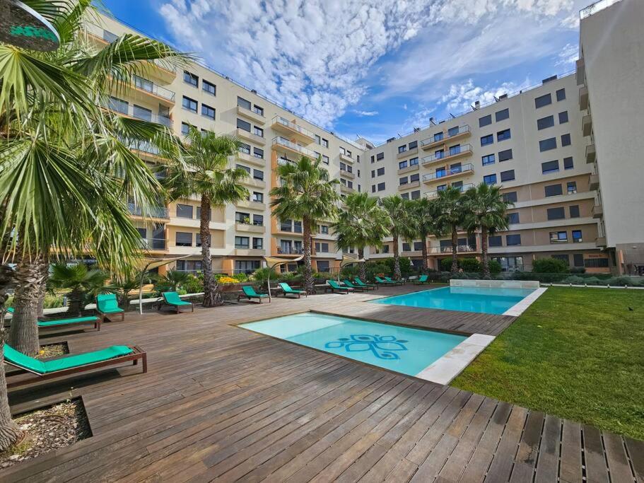 a large apartment building with a swimming pool and palm trees at River Terrace & Pool View - Seixal in Seixal