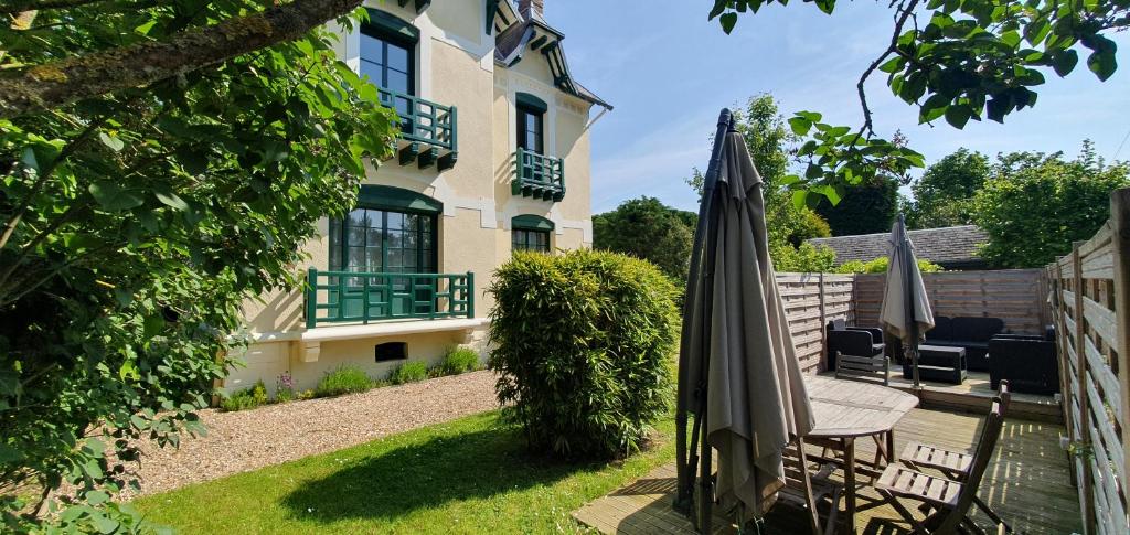 eine Terrasse mit Sonnenschirm und Stühlen und ein Haus in der Unterkunft Villa Simple Abri in Verneuil d’Avre et d’Iton