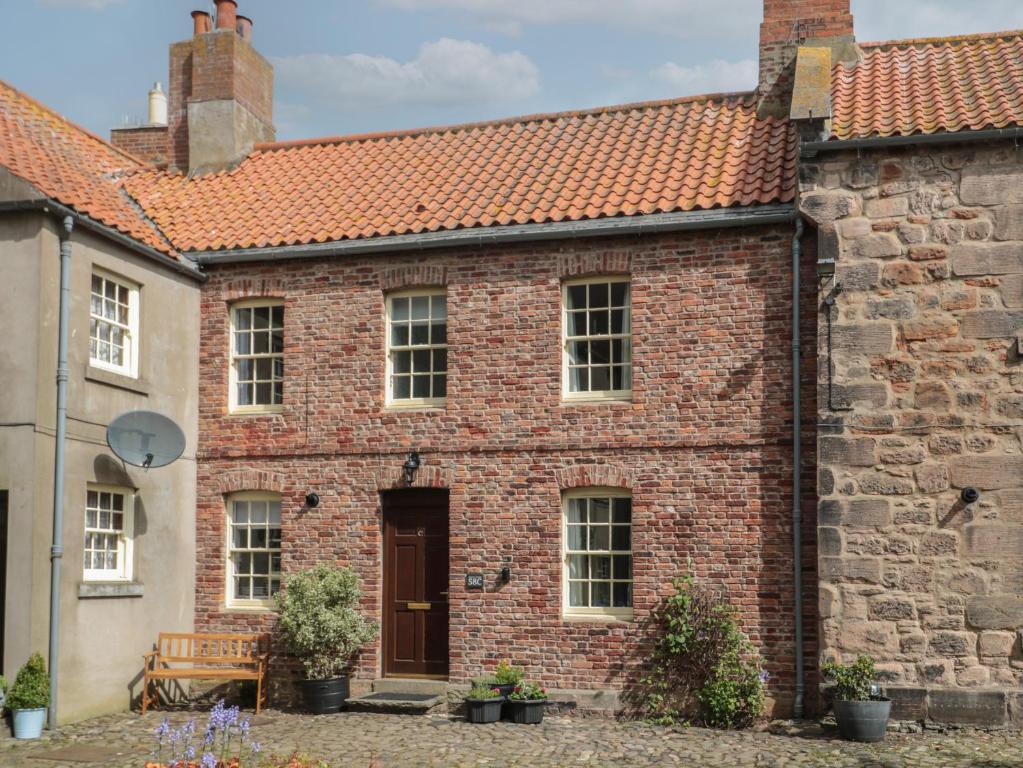 an old brick house with a red roof at Charter's Cottage in Berwick-Upon-Tweed