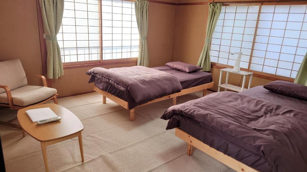 a bedroom with two beds and a chair and a table at GuestHouse AZMO - Vacation STAY 84356v in Matsue