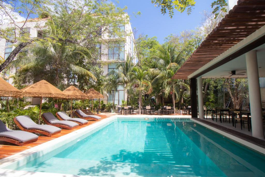 a pool at a hotel with chairs and umbrellas at Prana Boutique Hotel Tulum in Tulum