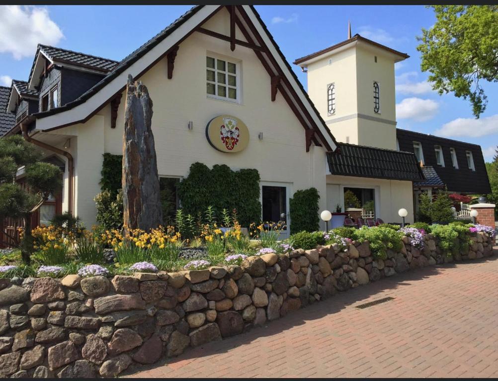 a building with a stone wall and flowers in front of it at Tangstedter Mühle in Tangstedt