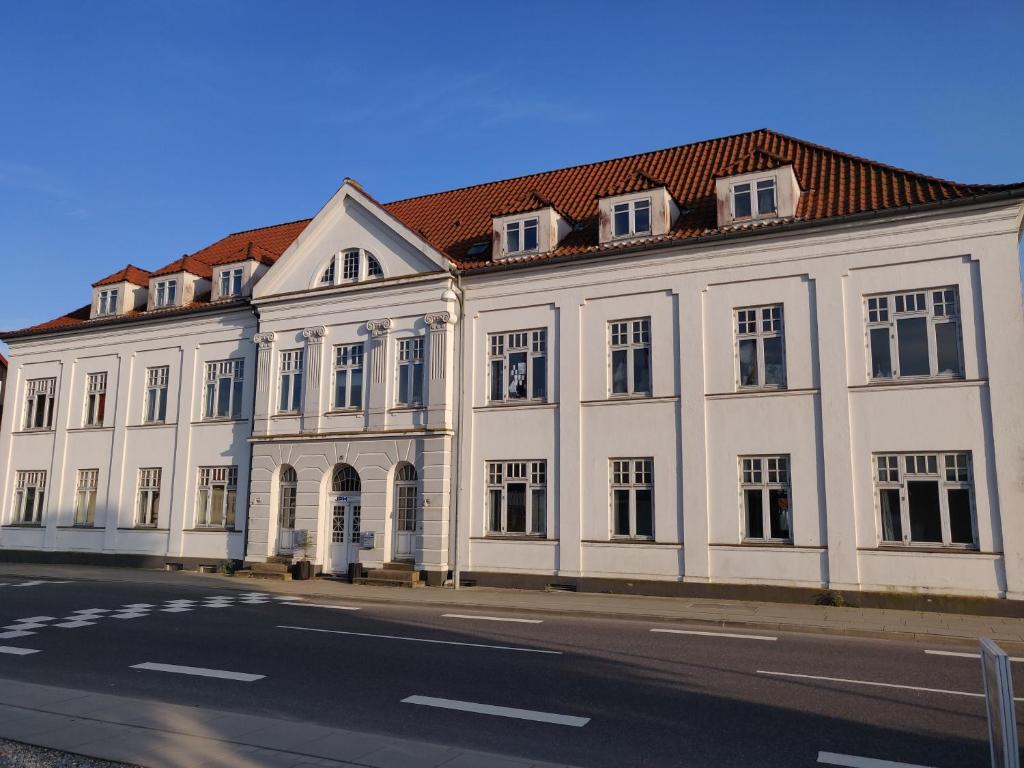 een groot wit gebouw met een rood dak bij Dronninglund Appartements in Dronninglund