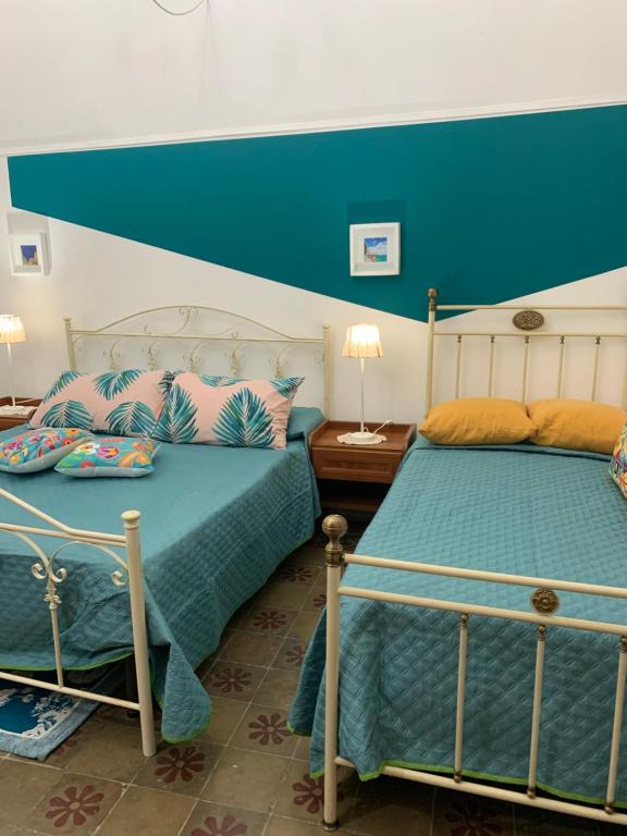 1 dormitorio con 2 camas y pared azul en Casetta del Borgo - Locazioni brevi, en Siracusa