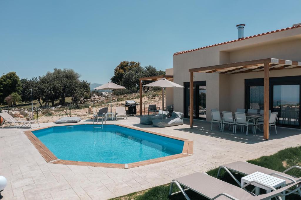een zwembad met een patio en een huis bij Jason Panorama Villa 2 in Skouloúfia