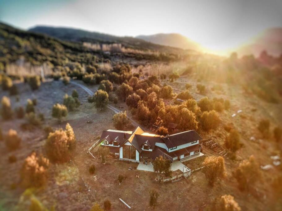 una casa en un campo con el sol en el fondo en ALOHA casa soñada en la montaña en San Martín de los Andes