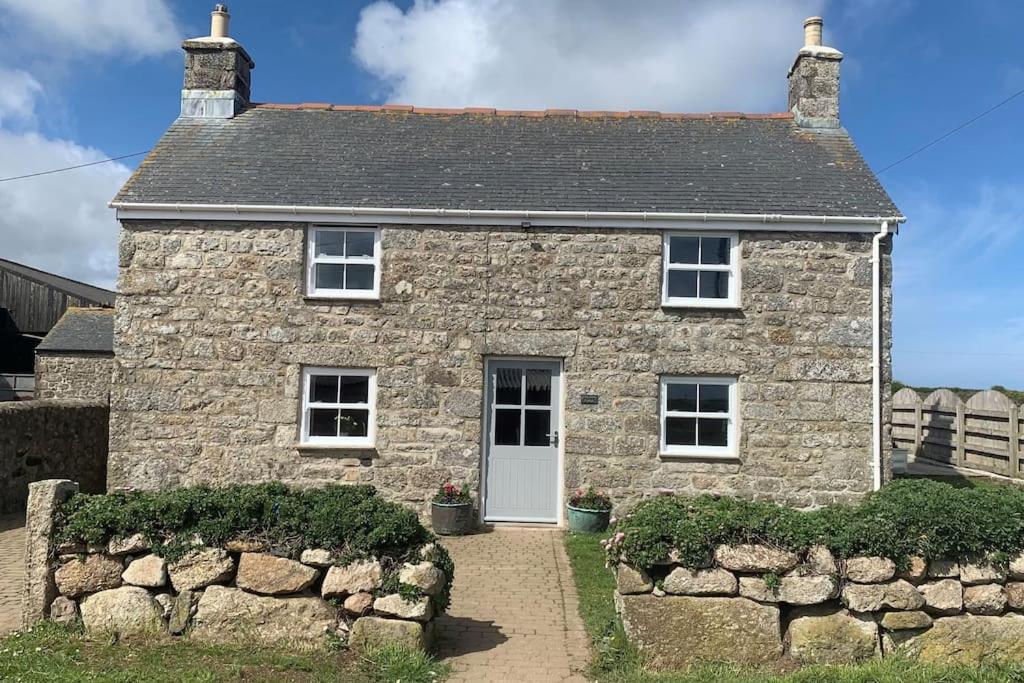 uma casa de pedra com uma porta branca em Folly Farm Cottage, Cosy, Secluded near to St Ives em St Ives