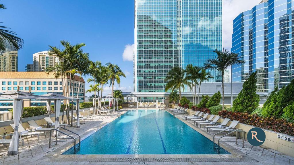 een zwembad met stoelen, palmbomen en gebouwen bij Roami at Brickell Penthouse Squad Oasis in Miami