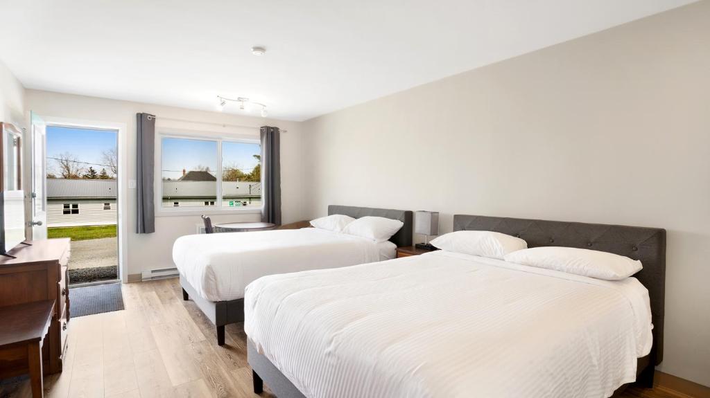 two beds in a room with two windows at Homeport Motel in Lunenburg