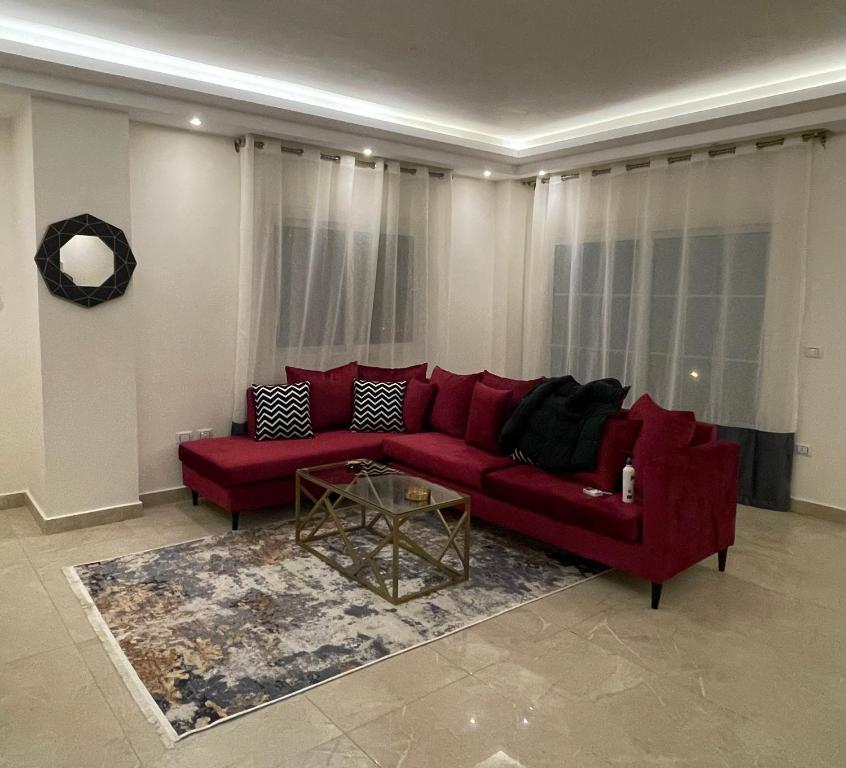 ein rotes Sofa im Wohnzimmer mit einem Tisch in der Unterkunft B-Home 2 in Kairo