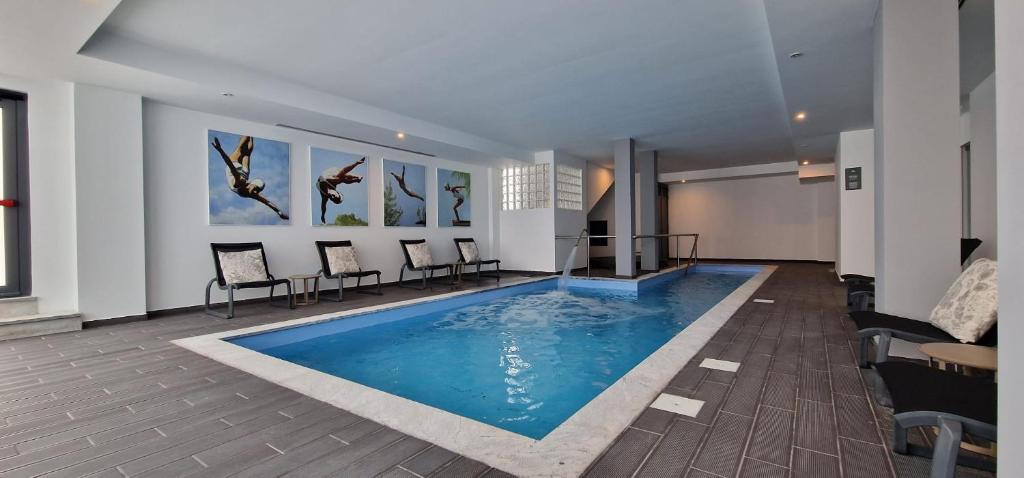 a swimming pool in a room with chairs and a table at Villa Rey Spa & Hotel in Vila de Rei