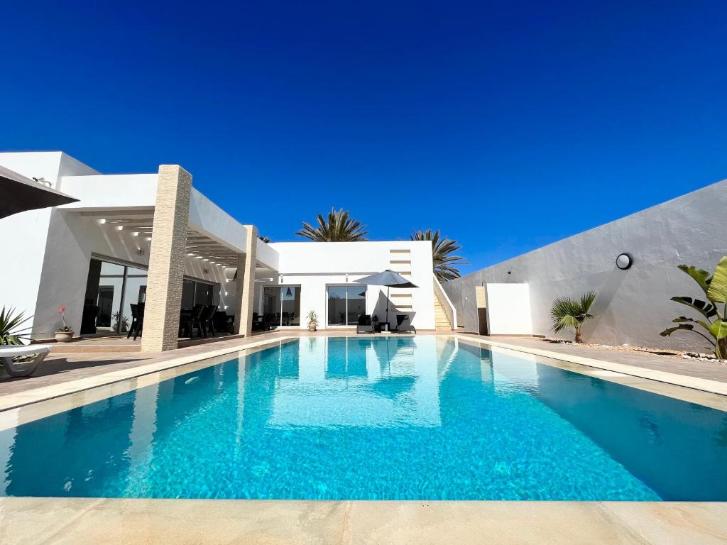 a large swimming pool in front of a house at Magnifique Villa moderne piscine SANS VIS À VIS DJERBA Midoun in Taguermess