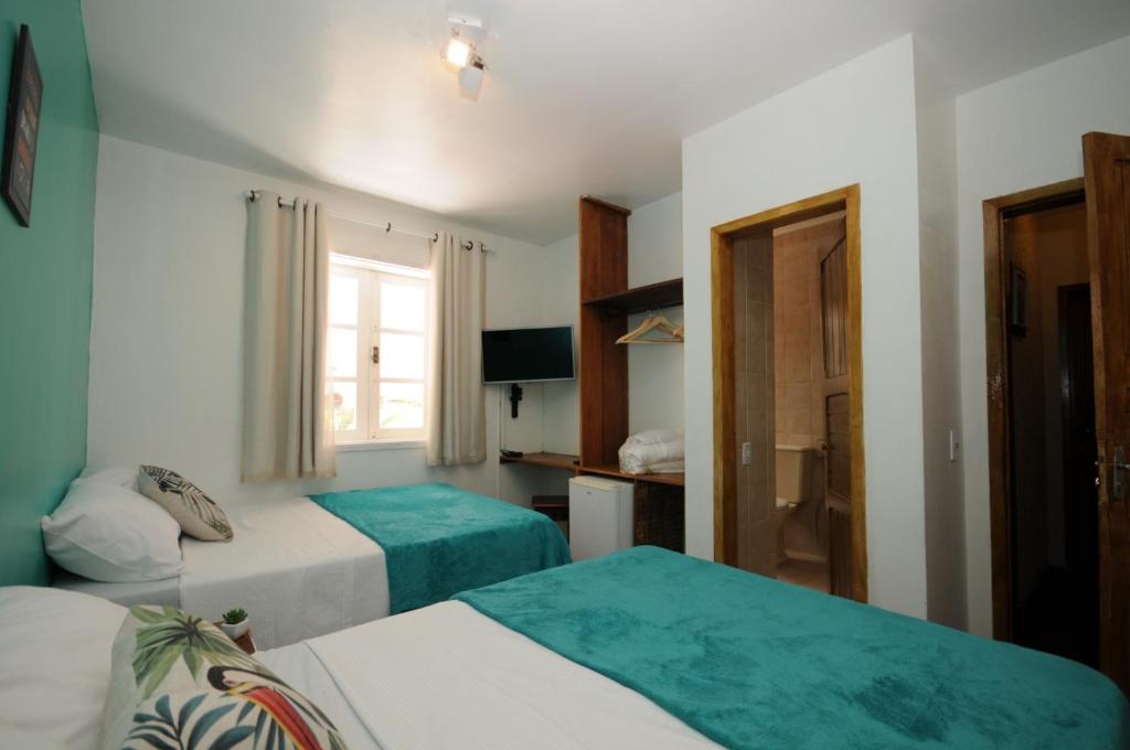Cette chambre comprend 2 lits et une fenêtre. dans l'établissement Pousada Mojomar Buzios, à Búzios