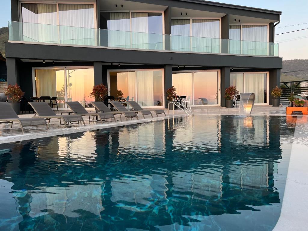 a building with a swimming pool and chairs in front of it at Casa Del Sol - Luxury Villas in Himare