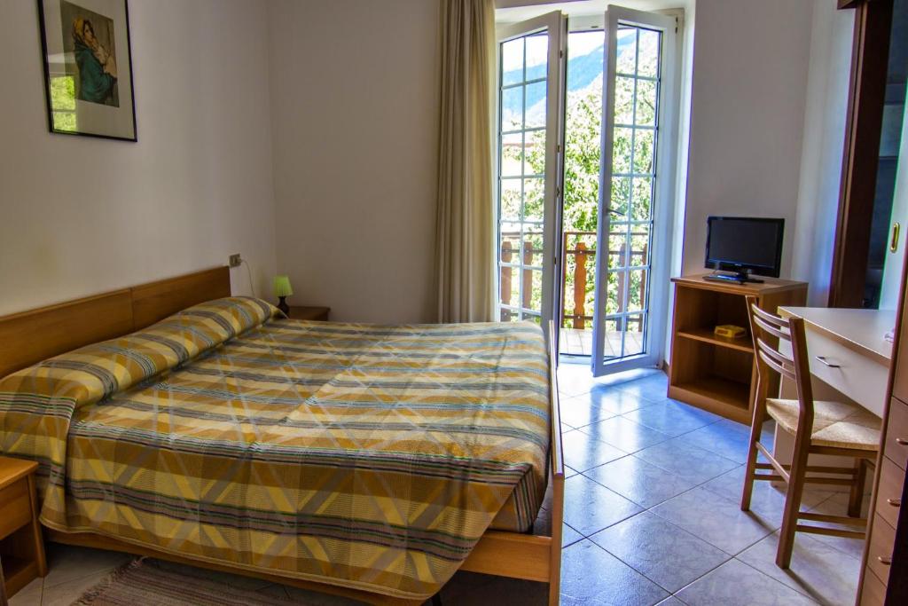 a bedroom with a bed and a television and a balcony at Belandin Ristorante Hotel in Teglio