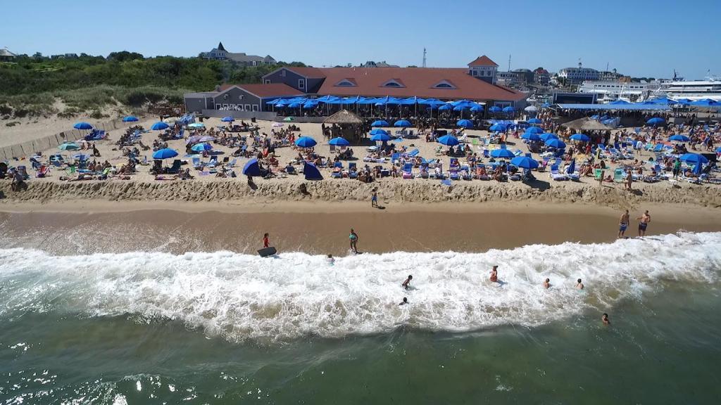 a beach with a crowd of people in the water at Ballard's Beach Resort in New Shoreham