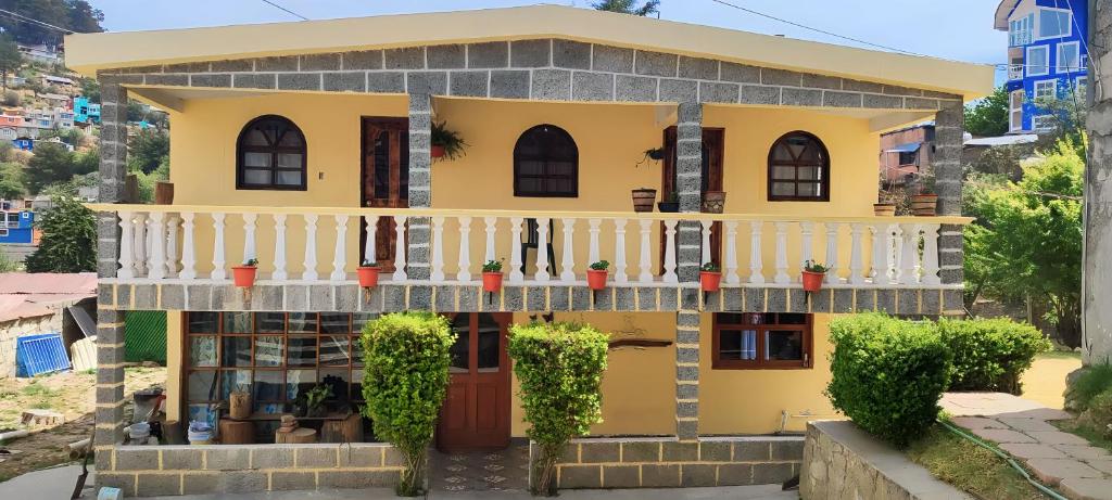 a yellow house with a white balcony at Cabaña Papá Beto in Mineral del Monte