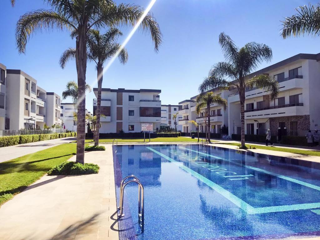 einen Pool mit Palmen und Gebäuden in der Unterkunft Appartement de vacances piscine in Mohammedia