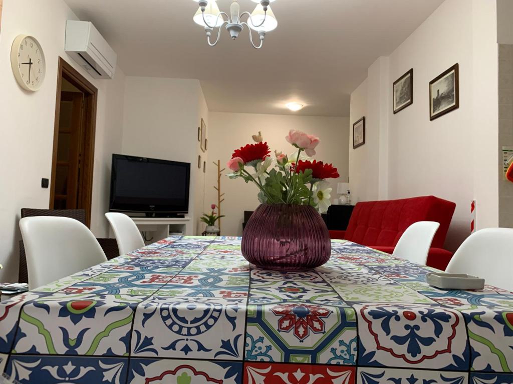 a dining room table with a vase of flowers on it at Alghero Heart in Alghero