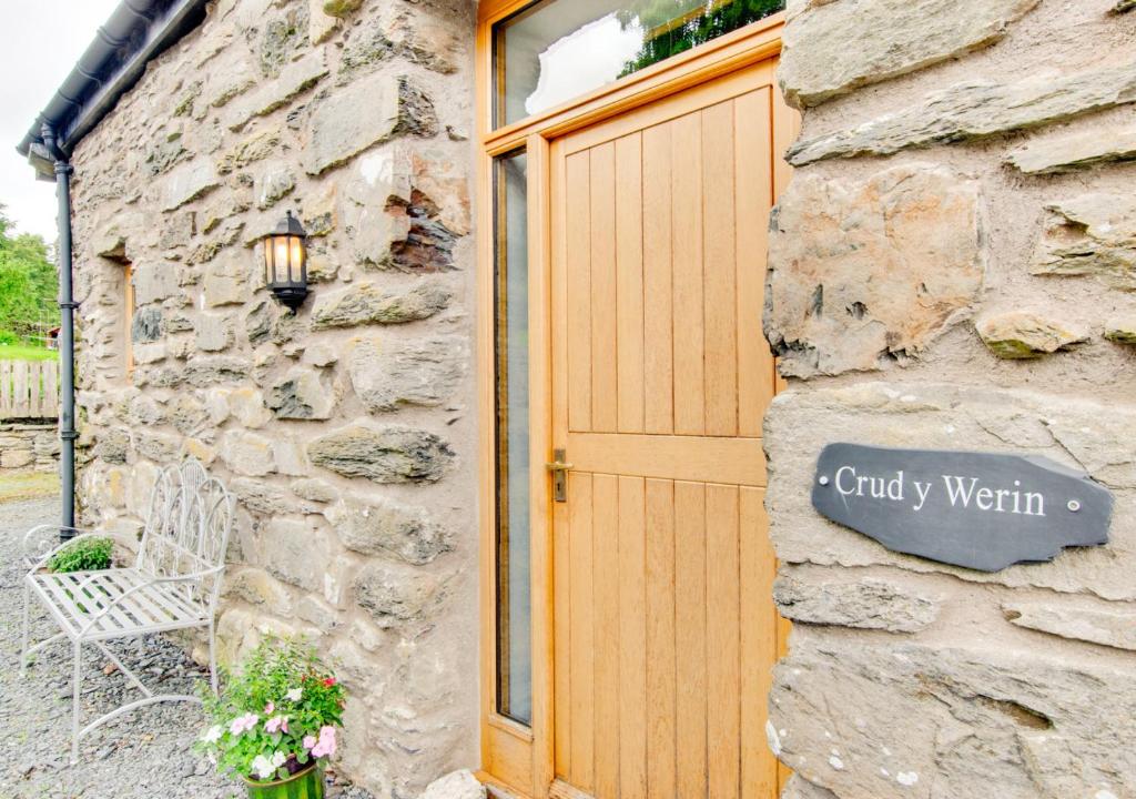 a stone building with a wooden door and a sign on it at Crud y Werin in Llandderfel