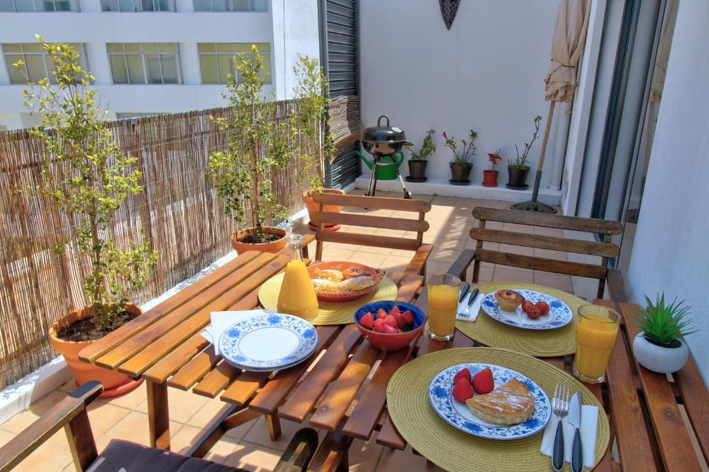 a wooden table with plates of food on a patio at Spacious terrace, swimming pool, private parking in Olhão