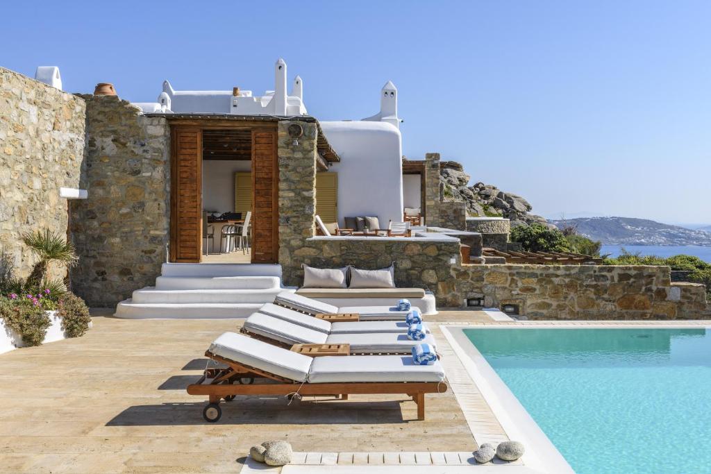 a group of lounge chairs next to a swimming pool at Villa Yasmina in Tourlos
