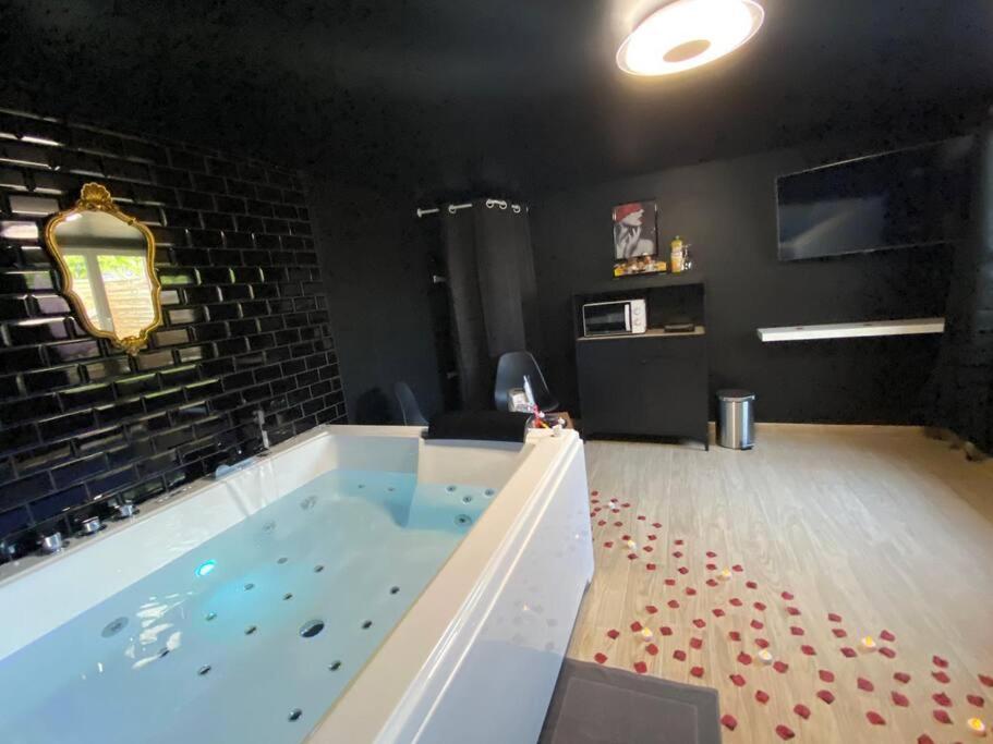 uma grande banheira de hidromassagem num quarto em Le CinéGlam Spa em Margny-lès-Compiègne