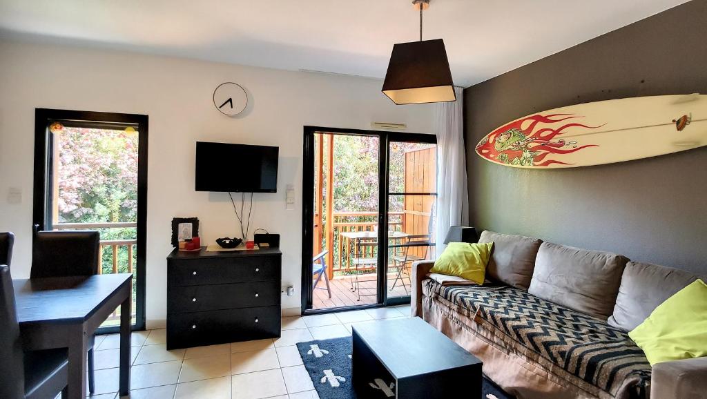 - un salon avec un canapé et une planche de surf sur le mur dans l'établissement A-Nature 01-Messsanges appartement 4 personnes dans résidence avec piscine, à Messanges