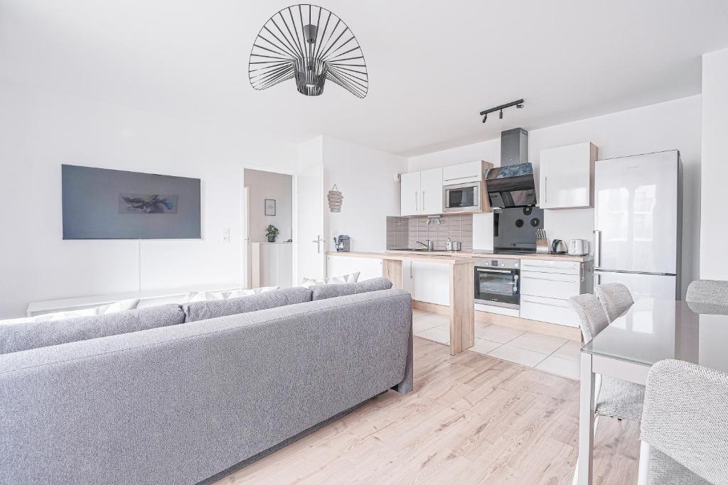 a living room with a couch and a kitchen at Coco - Appartement F4 à 10 minutes de Disneyland Paris in Bailly-Romainvilliers