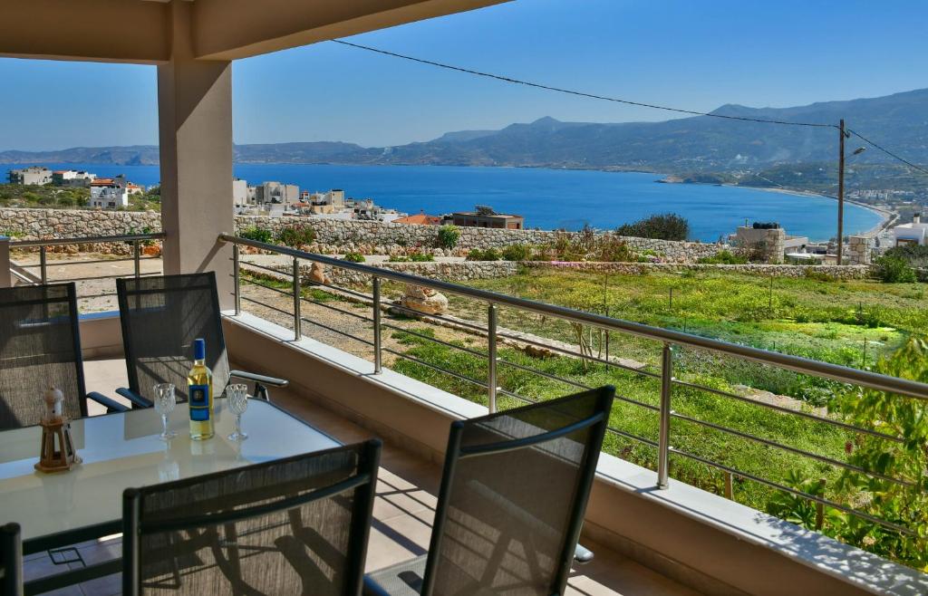 Sitia Bay View Villa Apartment في سيتيا: شرفة مع طاولة وكراسي وإطلالة على الماء