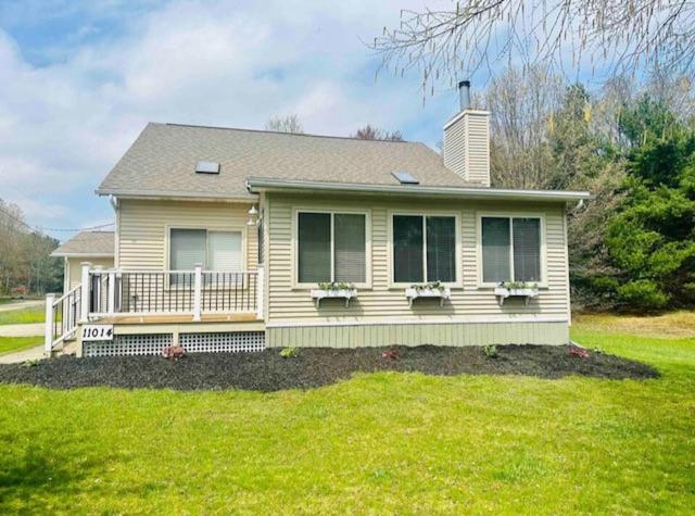une petite maison avec une terrasse couverte sur une pelouse verdoyante dans l'établissement Cozy Canadian Lakes Cottage, à Stanwood