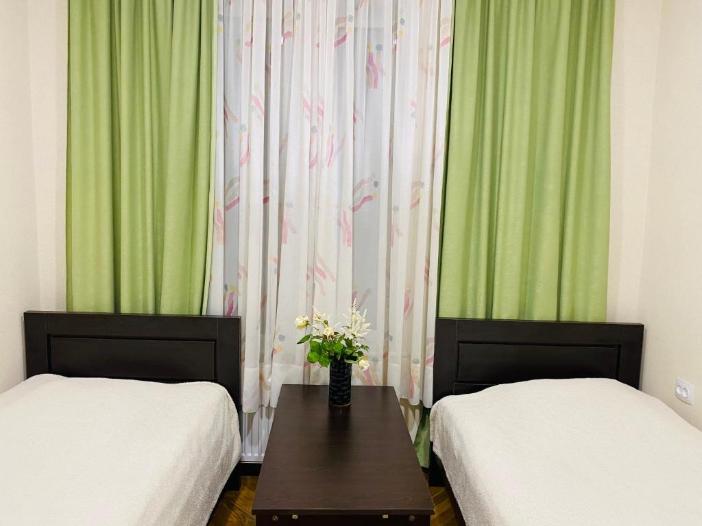 een kamer met 2 bedden en een tafel met bloemen bij At Nana's in Lagodekhi