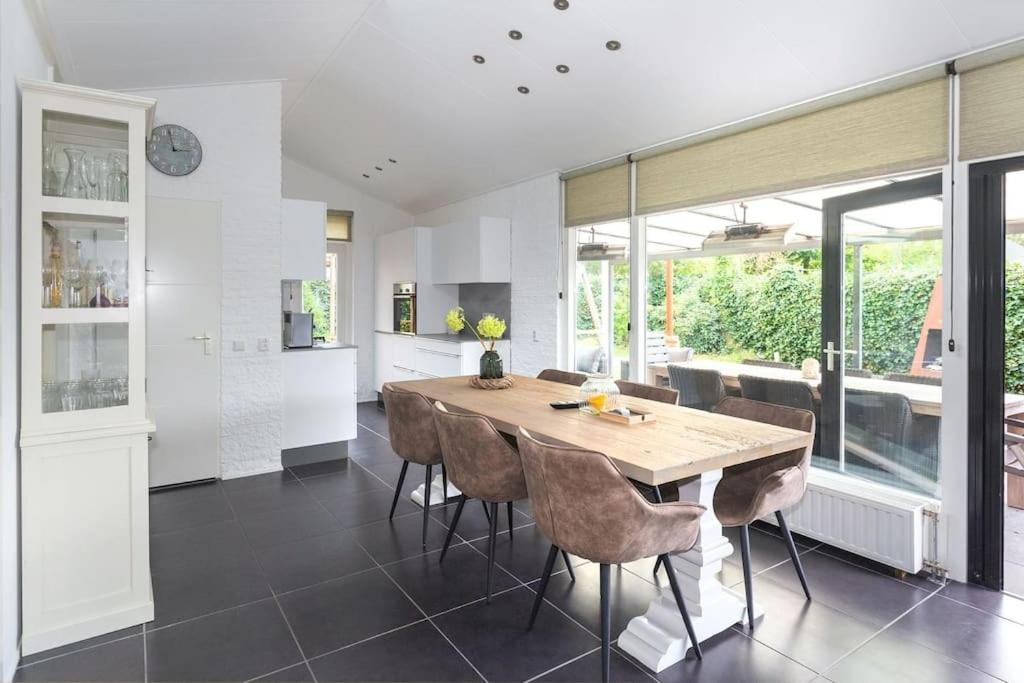 a kitchen and dining room with a wooden table and chairs at Bungalow near beach with large private garden - not for companies in Ouddorp